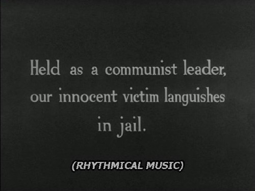 Caption, set in Verdana Italic, reads: (RHYTHMICAL MUSIC). Above it is a hand-lettered title reading: Held as a communist leader, our innocent victim languishes in jail