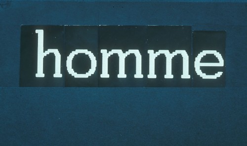 White letters on black paper, tacked onto a blue board, read ‘home’